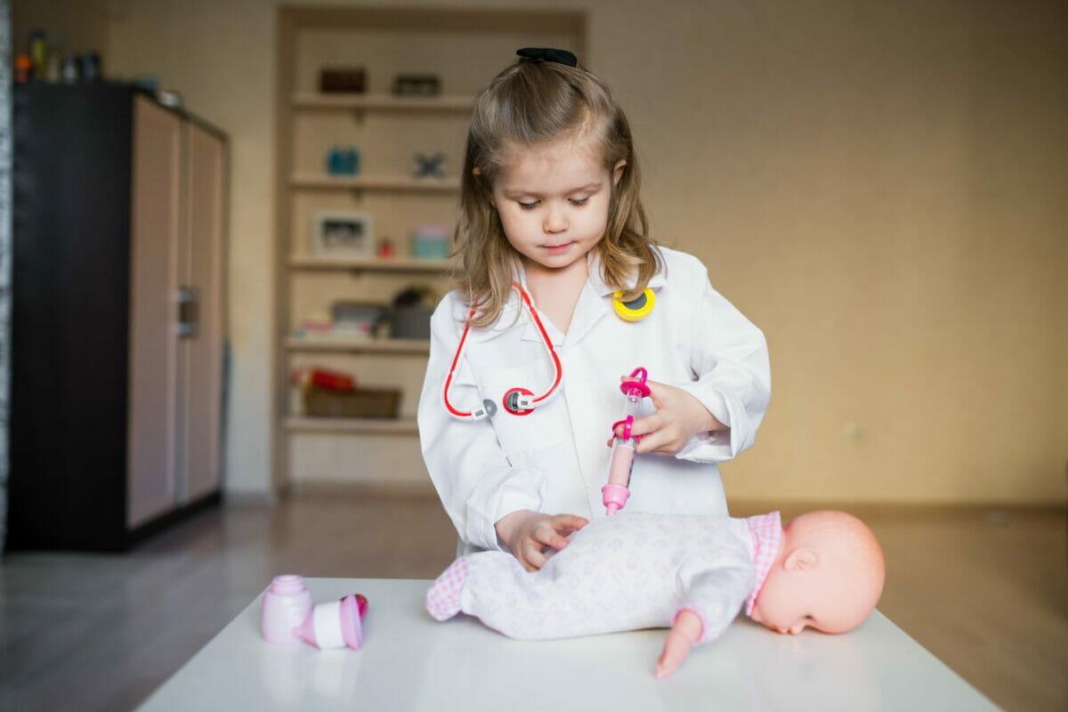 image of a girl playing doctor with a baby doll